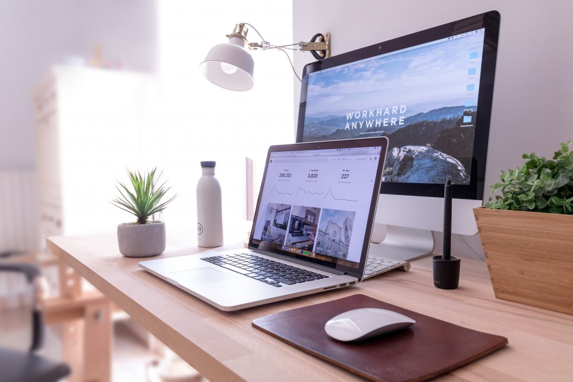 A desk with a laptop and desktop, both displaying examples for author websites.