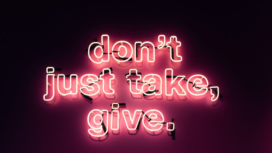 A red, pink, and white sign lights up to read, "don't just take, give."