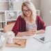 A full-time freelancer sits at her desk with her laptop in front of her, a cup of hot tea in hand.