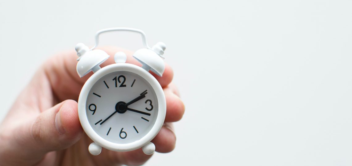 A small white clock slips through a person's fingers.