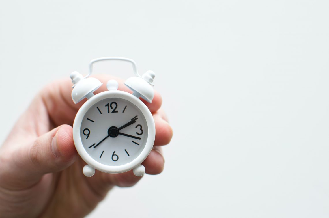 A small white clock slips through a person's fingers.