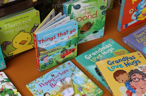 Multiple children's books stacked on a table.