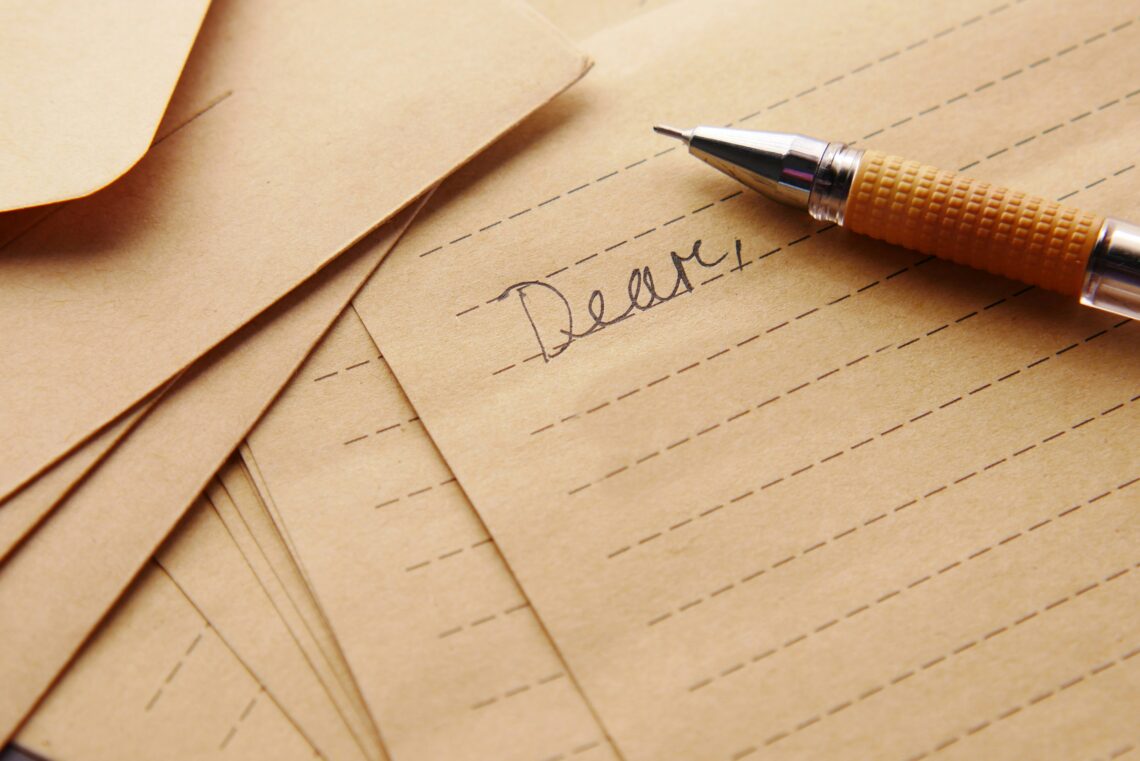 A letter with the word "Dear," written at the top of the paper accompanied by an old ink pen.