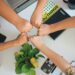 A group of people put their hands into a center circle, signifying teamwork.