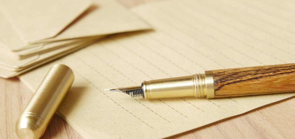 A blank piece of paper, with an old ink pen sitting on top.