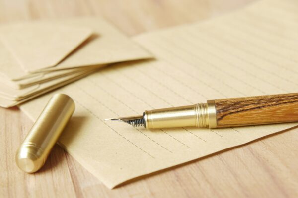 A blank piece of paper, with an old ink pen sitting on top.